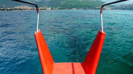 Téléchargez les photos : Vue de la queue du bateau rouge naviguant sur l'eau de mer calme au port. - en image libre de droit