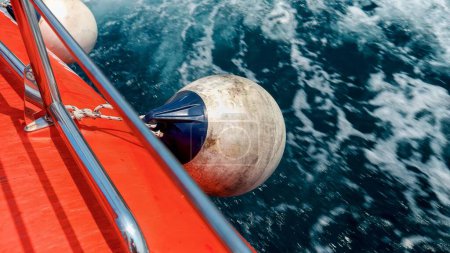 Photo for Closeup of fenders and buoys hanging on the side of red rescue boat sailing through cold northern sea. - Royalty Free Image