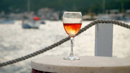 Téléchargez les photos : Gros plan de verre de vin sur la table de bar contre les vagues de la mer et jetée - en image libre de droit