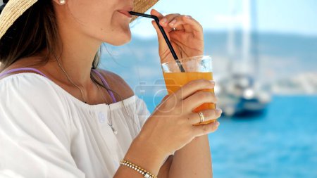 Téléchargez les photos : Dans un kiosque de café de plage sur la jetée, la brune profite de son jus d'orange. Essence de l'été, bonheur des vacances, détente, et l'attrait du voyage. - en image libre de droit