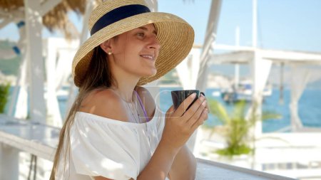 Téléchargez les photos : Dans un café au bord de la plage, une femme aime le café, symbolisant les vacances d'été et la détente côtière. - en image libre de droit