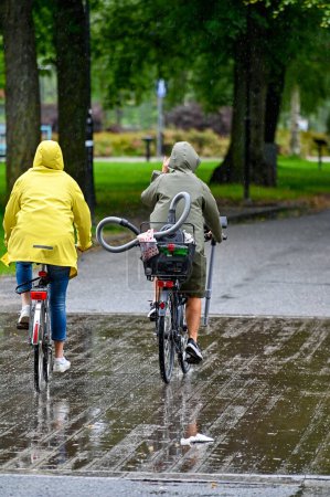 Photo for Rides bike through rain with vacuum cleaner in basket a rainy day in Orebro Sweden august 9 2023 - Royalty Free Image
