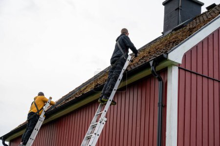 Foto de Trabajadores limpiando tejas cubiertas de musgo Kumla Suecia 29 septiembre 2023 - Imagen libre de derechos