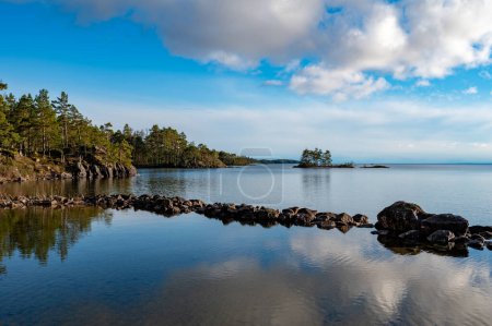 mirando hacia fuera sobre pequeño muelle de piedra en el lago tranquilo Motala Suecia abril 26 2024