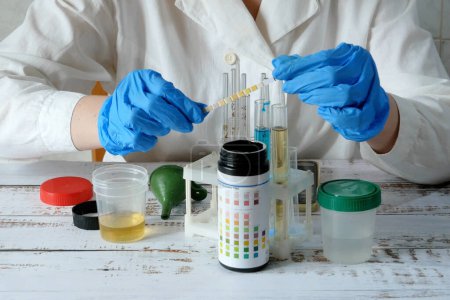 Photo for Medical laboratory assistant taking test tube with liquids, test with urine, Scientist doctor looking at sample in test tube. Laboratory analysis. Closeup - Royalty Free Image