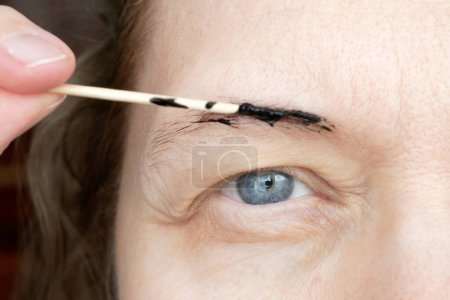Téléchargez les photos : Correction of eyebrows and modelling at home, eyebrow coloring henna tattooing, permanent makeup, closeup - en image libre de droit