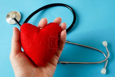 Foto de Red heart symbol in hand on blue background. american heart month in February, closeup - Imagen libre de derechos