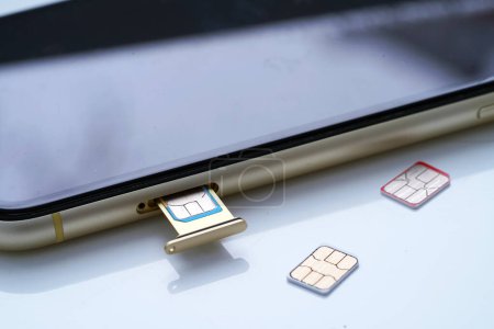 Photo for Person inserting a sim card into back of mobile phone, Sim card in tray being inserted into phone, closeup - Royalty Free Image