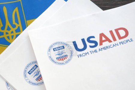 Foto de Kiev, Ucrania - 02 12 2023: Logotipo de USAid y bandera ucraniana, USAid es la agencia de EE.UU. para el desarrollo internacional - asistencia en el extranjero, primer plano - Imagen libre de derechos