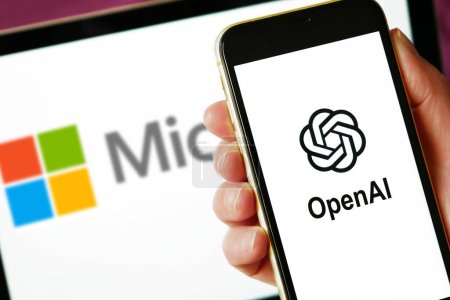 Photo for Lviv, Ukraine - 03 11 2023: hand holding smartphone with OPENAI logo on screen and laptop display with MICROSOFT logo on the background. Closeup - Royalty Free Image