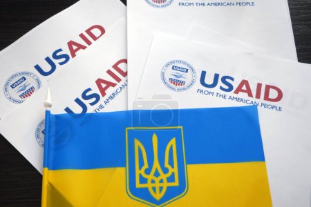 Foto de Kiev, Ucrania - 02 12 2023: Logotipo de USAid y bandera ucraniana, USAid es la agencia de EE.UU. para el desarrollo internacional - asistencia en el extranjero, primer plano - Imagen libre de derechos