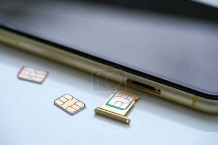 Photo for Person holding a sim card into back of mobile phone, Sim card in tray being inserted into phone, - Royalty Free Image