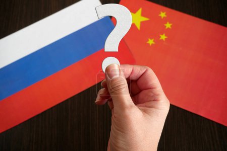 Téléchargez les photos : Mains tenir le point d'interrogation sur le fond des drapeaux de la Russie et de la Chine, Les pays sont-ils partenaires ou concurrents ? concept, gros plan - en image libre de droit