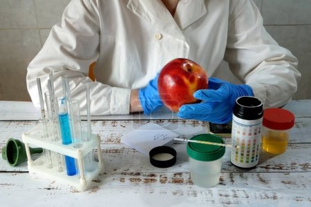 Photo for Medical laboratory assistant taking apple on  test tube with liquids background, test with urine, Scientist doctor looking at sample in test tube. Laboratory analysis. Closeup - Royalty Free Image