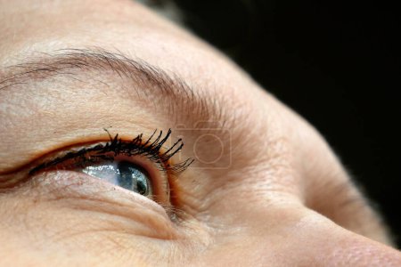 middle aged female's eye with drooping eyelid making eyebrow makeup. Ptosis is a drooping of the upper eyelid, lazy eye. Cosmetology and facial concept, first wrinkles, closeup