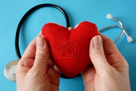 Red heart symbol in woman hands on blue background. american heart month in February, closeup