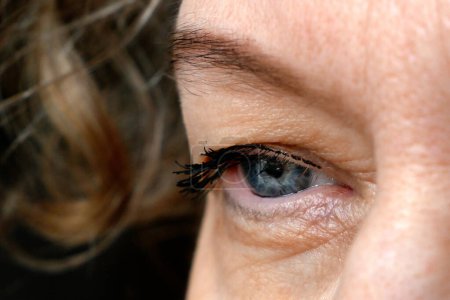 middle aged female's eye with drooping eyelid making eyebrow makeup. Ptosis is a drooping of the upper eyelid, lazy eye. Cosmetology and facial concept, first wrinkles, closeup