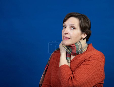 Photo for Woman in an orange sweater in the studio. High-quality photo was taken on a blue background with a campy pose. - Royalty Free Image