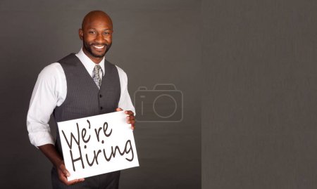 Foto de Fueron la contratación - Joven hombre de negocios negro con una tarjeta blanca que indica el estado de contratación - Imagen libre de derechos