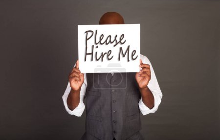 Photo for Please Hire Me - Young black businessman holding a white card indicating desire to work - Royalty Free Image