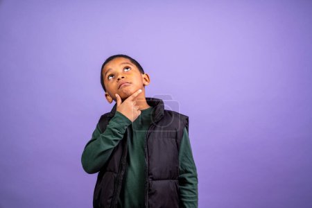 Téléchargez les photos : Jeune garçon lève les yeux dans l'émerveillement avec la main sur son menton avec de la place pour la copie sur le dessus et les côtés - en image libre de droit
