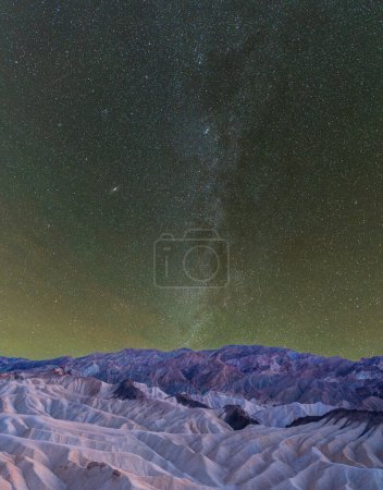 La Voie lactée au-dessus d'un paysage désertique dans la Vallée de la Mort avec de la pollution lumineuse à l'horizon