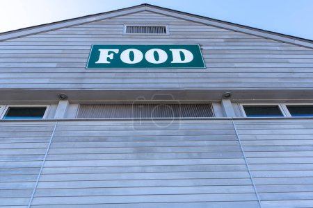Téléchargez les photos : Un bâtiment avec une pancarte verte qui dit de la nourriture dessus. Le bâtiment est blanc et a des fenêtres - en image libre de droit