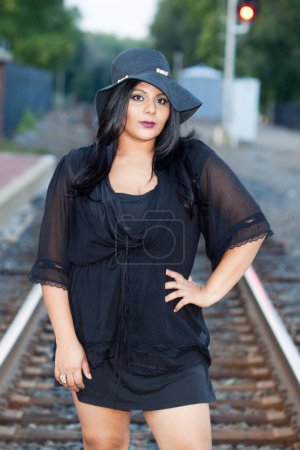 Téléchargez les photos : Une Indienne d'Asie du Sud en surpoids et à la mode attend debout sur les rails d'une gare - en image libre de droit