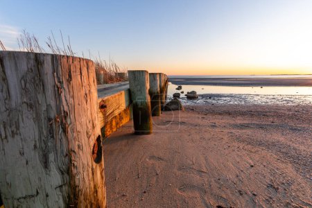 Ein Holzsteg mit einem Holzsteg, der zum Strand führt. Der Steg ist von Wasser und Sand umgeben