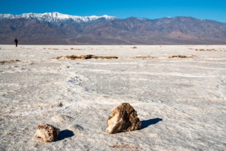 Téléchargez les photos : Une personne marche dans le désert avec une montagne en arrière-plan. Le désert est sec et rocheux, avec quelques petits rochers éparpillés autour. La personne semble profiter de la solitude - en image libre de droit