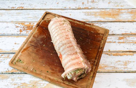 Photo for Preparation of a porchetta with a mixture of aromatic herbs placed on a piece of fresh pork belly open in the thickness - Royalty Free Image