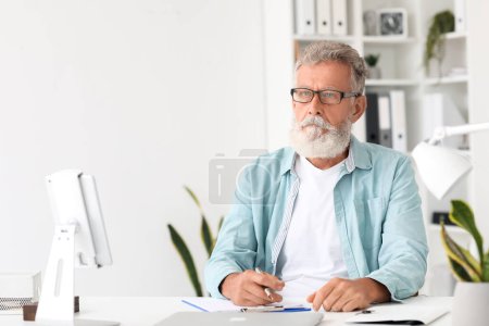 Senior bearded man working at table in office