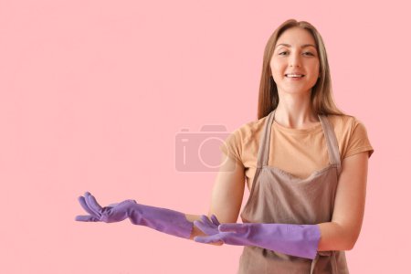 Téléchargez les photos : Jeune femme avec des gants en caoutchouc pointant quelque chose sur fond rose - en image libre de droit
