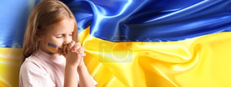 Photo for Praying little girl against flag of Ukraine - Royalty Free Image