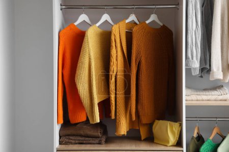 Photo for Warm knitted sweaters hanging in wardrobe - Royalty Free Image