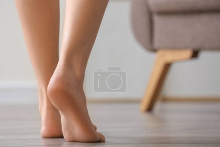 Téléchargez les photos : Femme pieds nus marchant sur le sol en bois à la maison - en image libre de droit