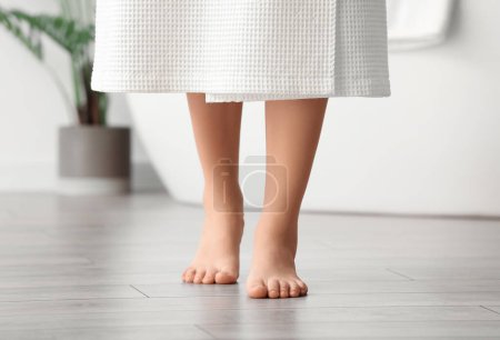 Téléchargez les photos : Femme pieds nus sur le sol dans la salle de bain - en image libre de droit