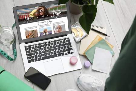 Female lifestyle blogger with laptop, mobile phone, glass of water and skincare products on light wooden floor Poster 618974230