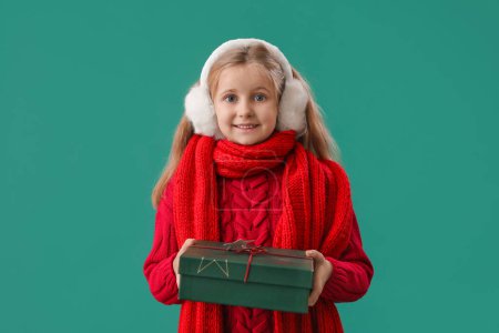Foto de Niña en orejeras con regalo de Navidad sobre fondo verde - Imagen libre de derechos