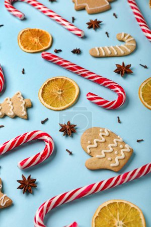 Téléchargez les photos : Composition avec de savoureuses cannes de bonbons, biscuits, épices et tranches d'orange séchées sur fond de couleur - en image libre de droit