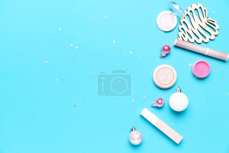 Makeup products with Christmas decor on blue background Poster 620168094
