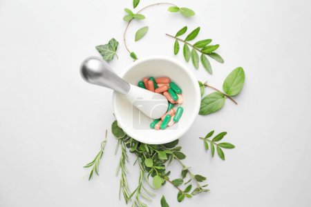 Photo for Mortar with pills and different herbs on white background - Royalty Free Image
