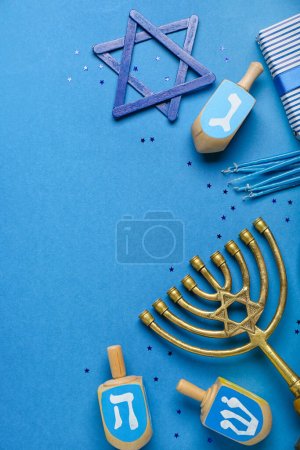 Dreidels with menorah, candles and David star for Hanukkah celebration on blue background