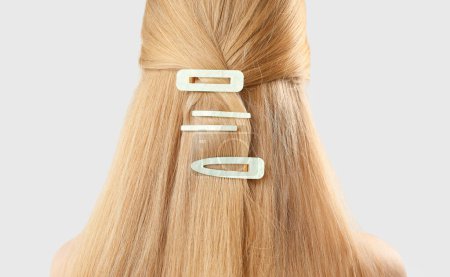 Photo for Blonde woman with long hair and stylish hairpins on light background, closeup - Royalty Free Image