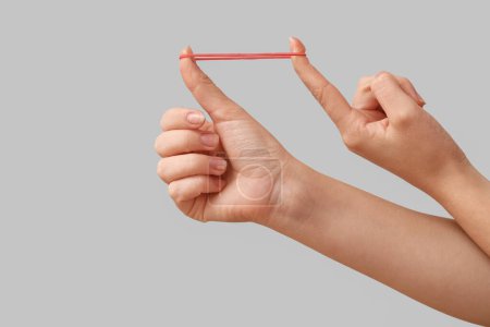 Woman with red rubber band on grey background