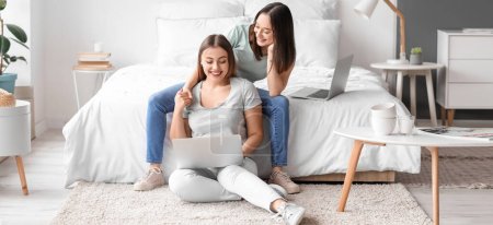 Photo for Young lesbian couple with laptop in bedroom - Royalty Free Image