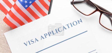Visa application form and USA flag on table, closeup. Concept of immigration