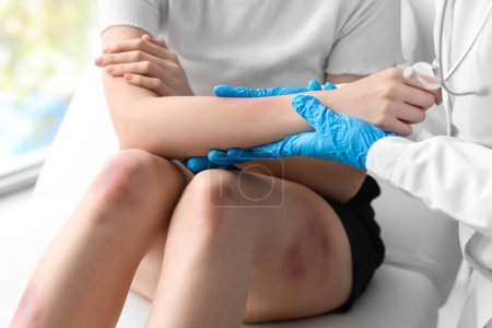 Photo for Female doctor examining patient's bruised arm in clinic, closeup - Royalty Free Image