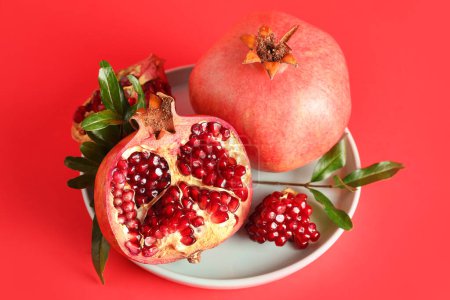 Photo for Plate with fresh pomegranates on red background - Royalty Free Image