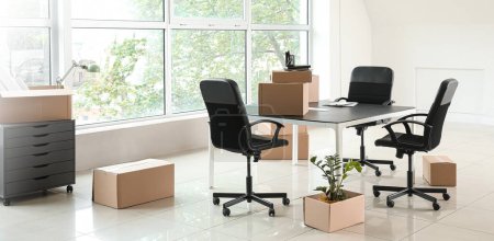 Téléchargez les photos : Boîtes en carton avec effets personnels et mobilier dans un nouveau bureau le jour du déménagement - en image libre de droit